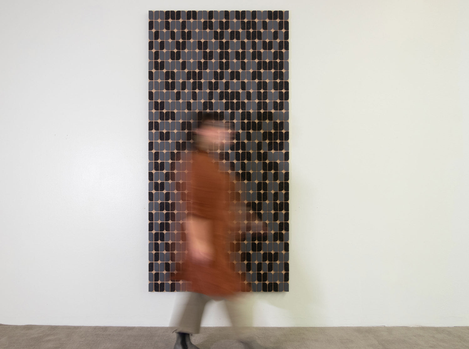 A sunny modern living room space with a desk, Modernica planter with tall thin plant, yellow modern couch and a subtly textured gray wall art piece hanging above the couch.