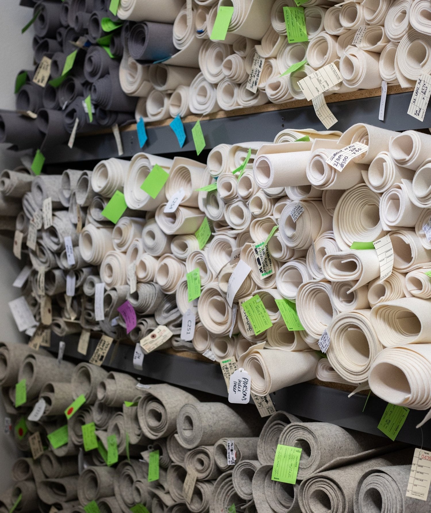 Shelves with white and gray rolls of felt with tags attached to the end.