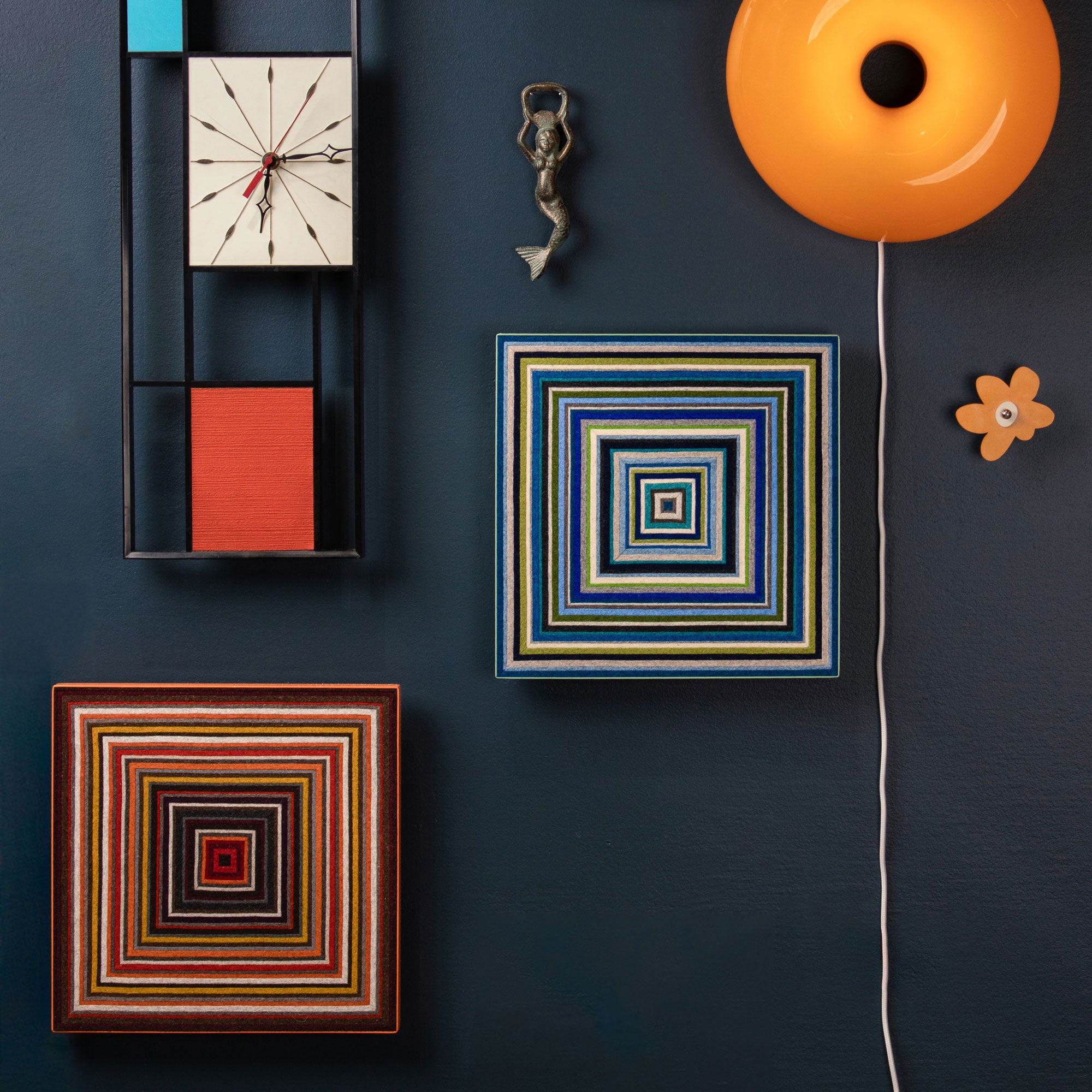 Decorative wall art pieces including a clock, square frames, and a lamp on a dark blue wall.
