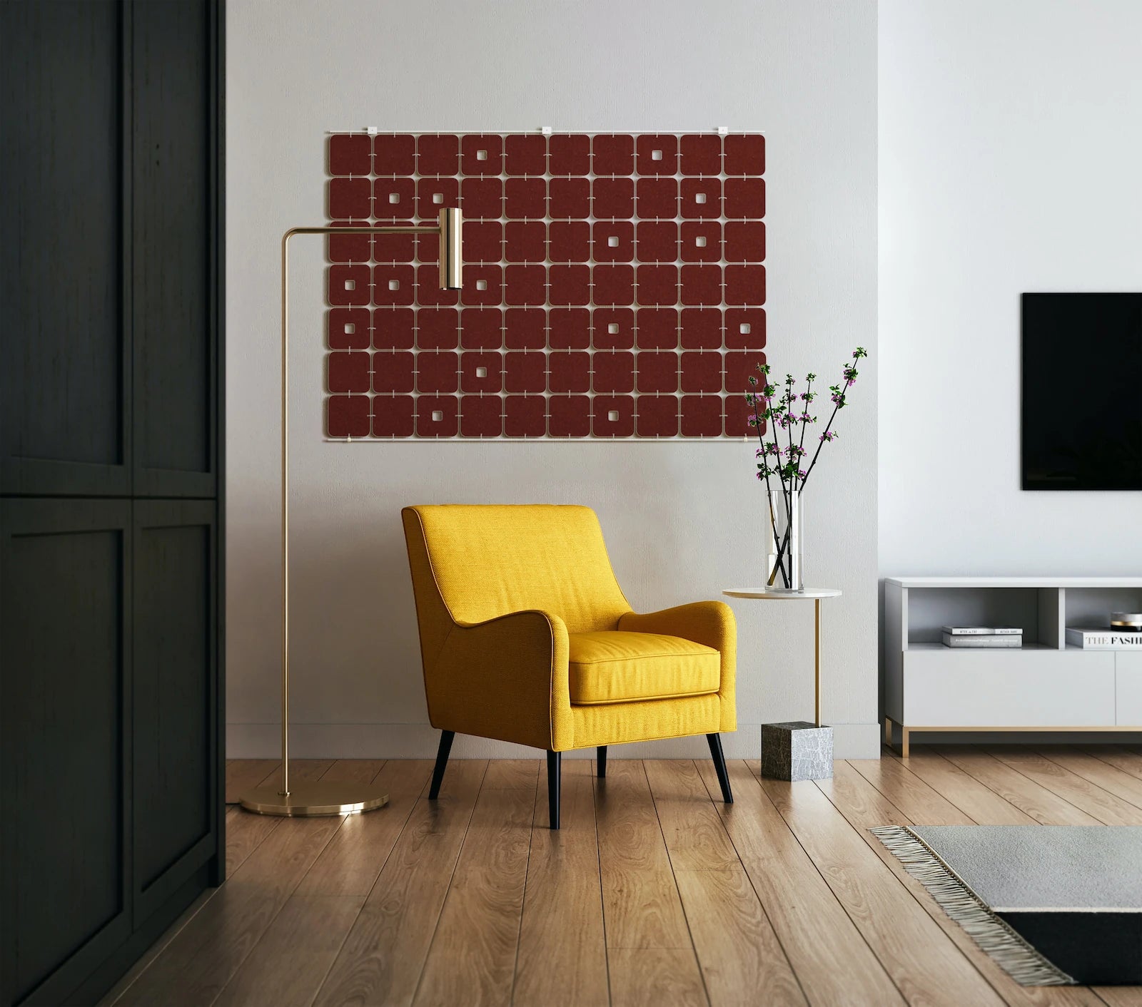 A wool felt wall hanging with softly curved squares and occasional keyholes in a maroon color hangs in a living room space. A yellow chair side table, a modern lamp sits in front of the hanging.