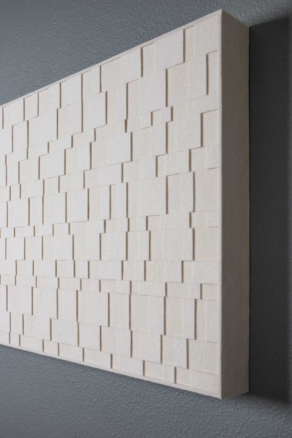 An Aerial wall panel seen from the side. A rectangular wall art piece of white felt in various sizes and layers.