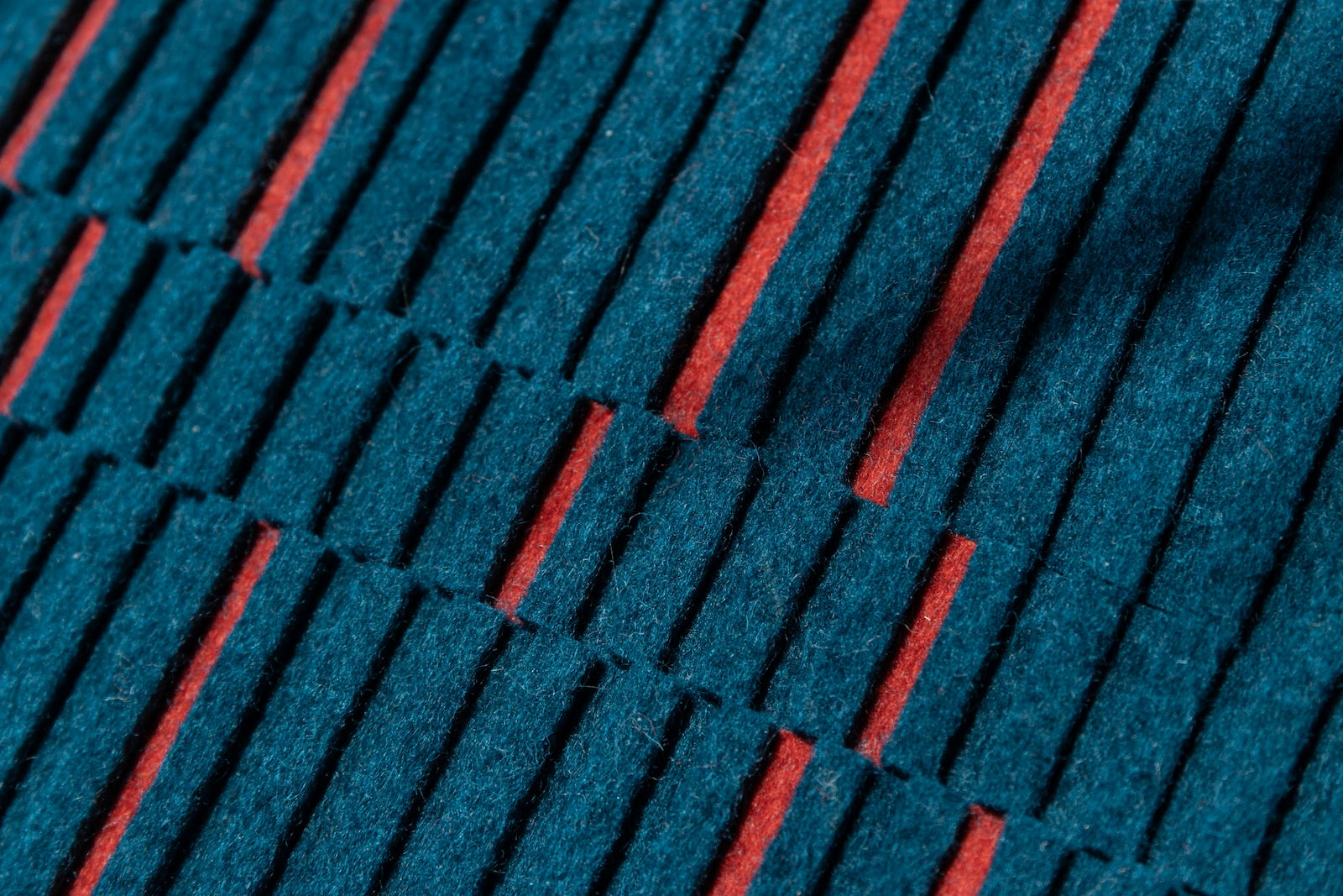 A closeup of blue wool felt with alternating height strips and random strips of red felt.