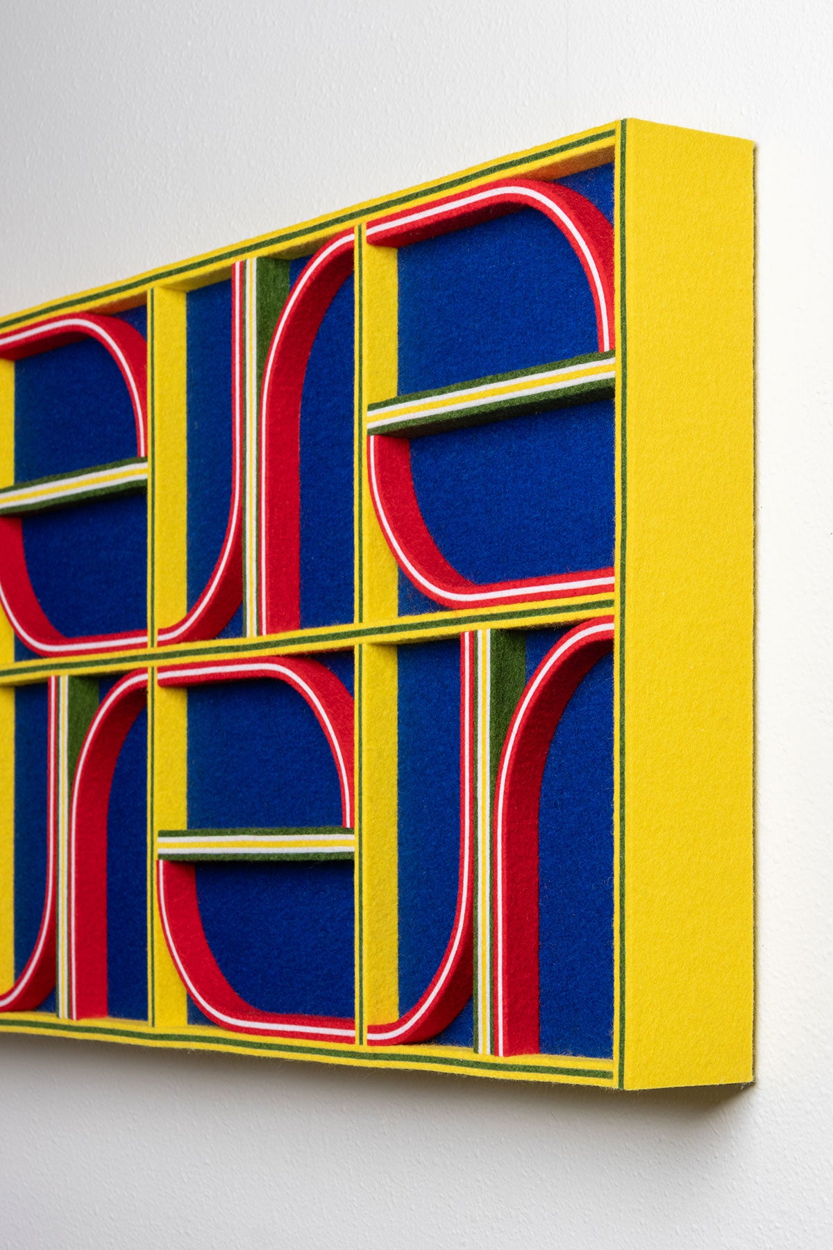 A view of the side of a felt panel in primary colors (yellow, blue, red) and a pattern of straight and curved lines.