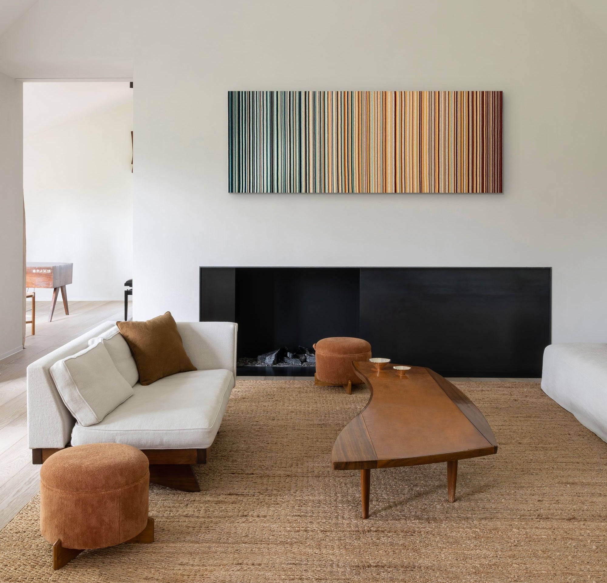 Modern living room with a white sofa, wooden coffee table, and abstract wall art.