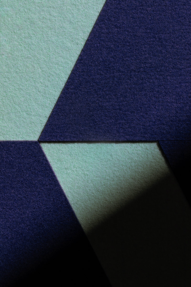 Closeup up detail of a felt wall art panel with a light blue and dark blue felt in large geometric shapes.