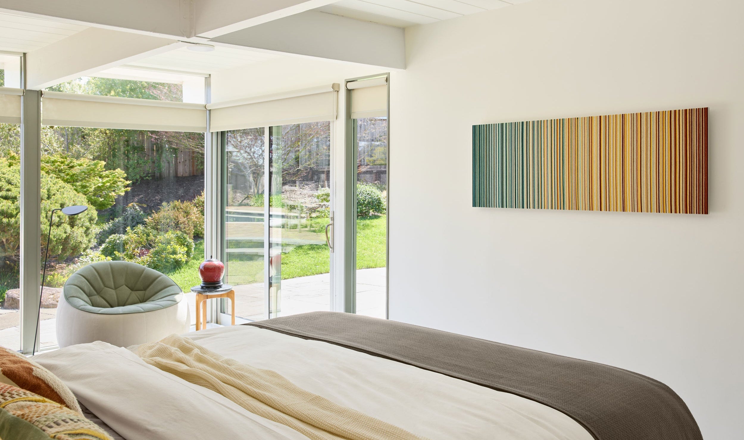 Modern bedroom with a bed, chair, and wall art