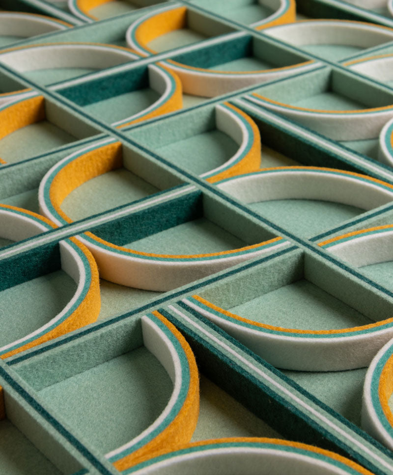 Close-up of a geometric-patterned felt surface with green, gray, and yellow colors.
