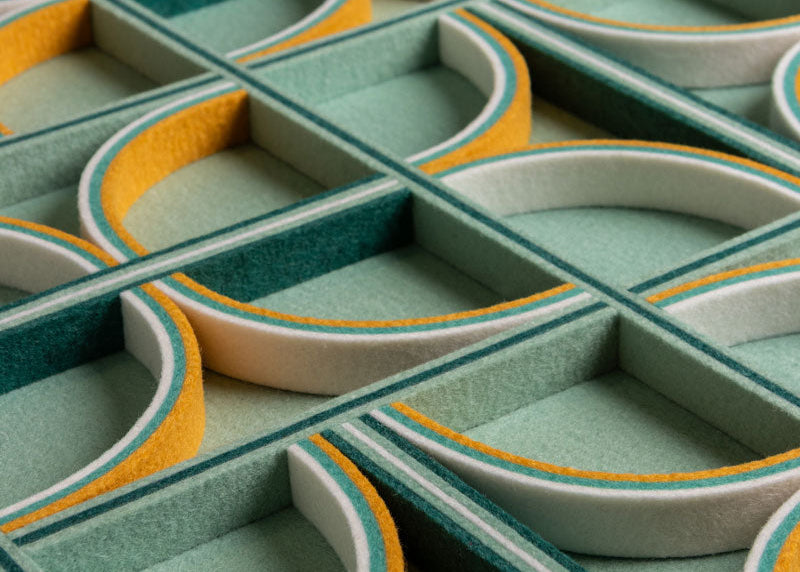 Close-up of a geometric-patterned felt surface with green, gray, and yellow colors.
