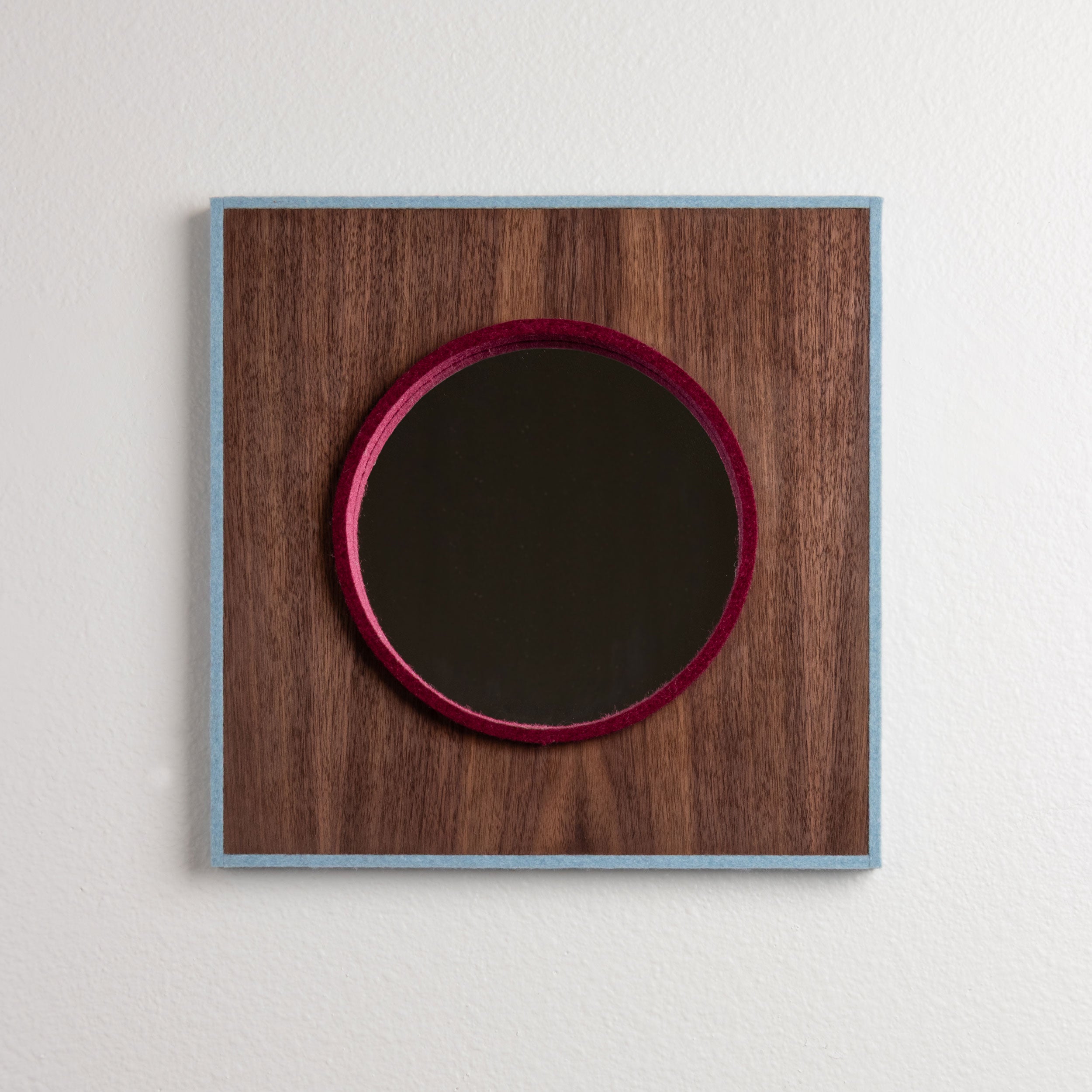 Square wood frame surrounded with a stripe of pale blue wool felt with a circular mirror with a dark red felt trim.
#color_Mini Round | Ice-Garnet