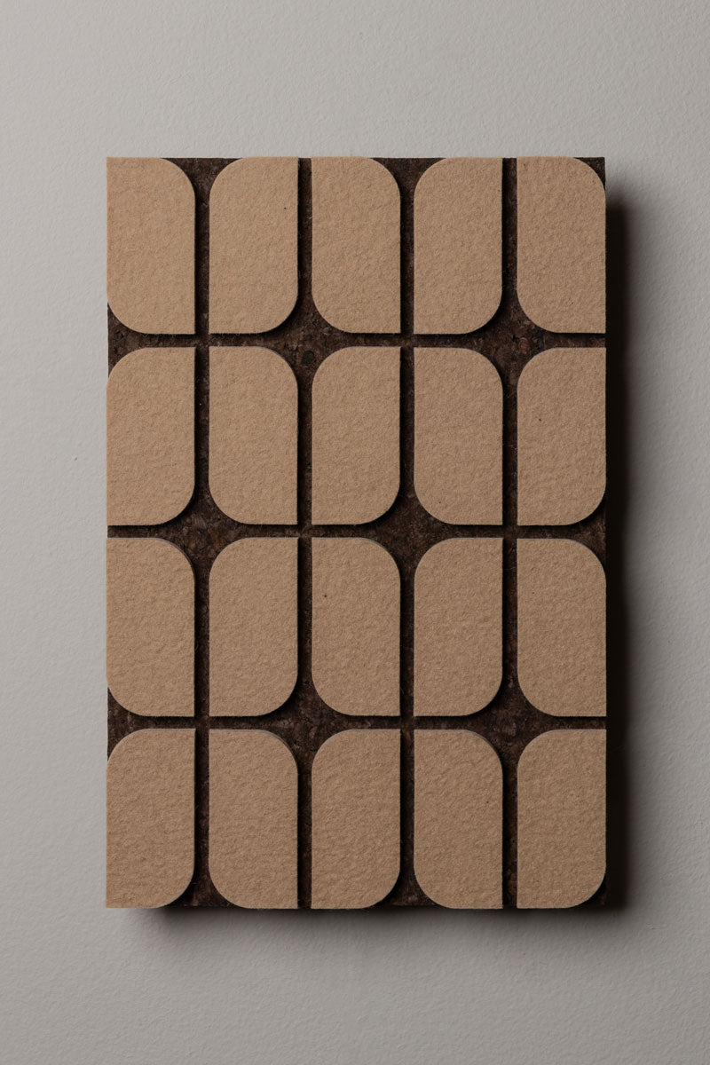 A flat wall panel with a geometric pattern consisting of curved-edge rectangular shapes, with a dark smoked cork background and tan felt details.
