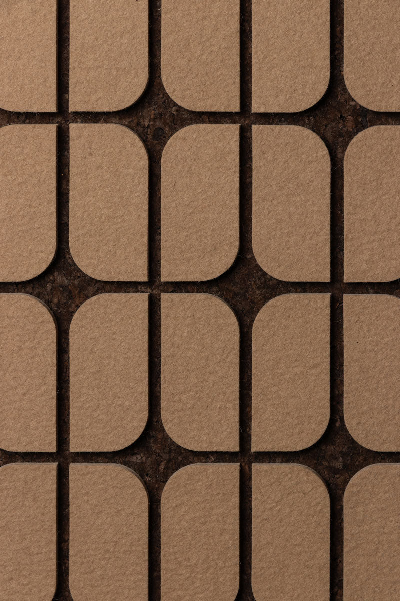 Close up of A flat wall panel with a geometric pattern consisting of curved-edge rectangular shapes, with a dark smoked cork background and tan felt details.