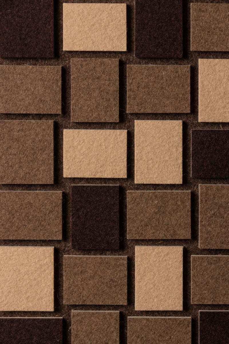 Close up of a geometric pattern of slight wool felt rectangles in beige and brown tones.