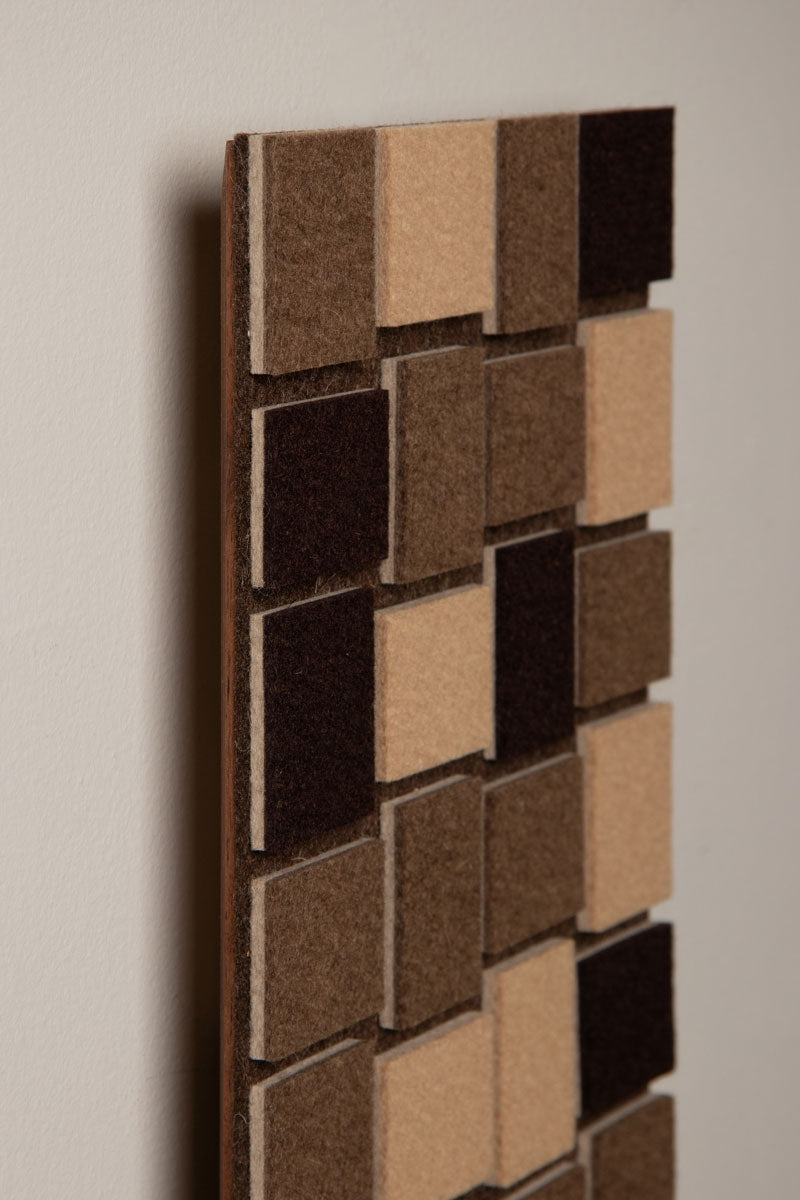 The top corner of a long, thin vertical Odessa Flat panel with a geometric pattern of slight rectangles in beige and brown tones, on a white wall.