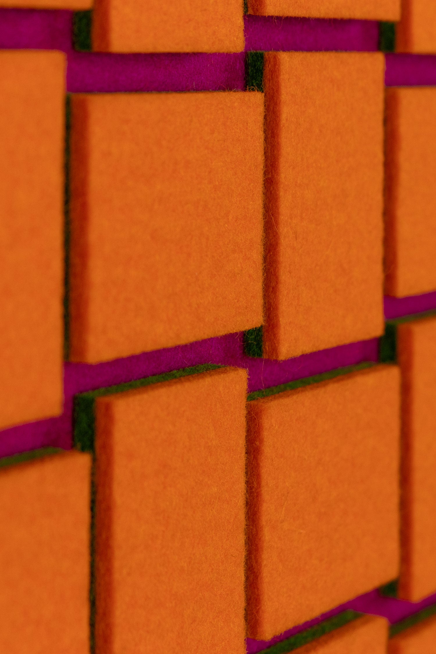 Close-up of orange, purple and green felt wall art panel.