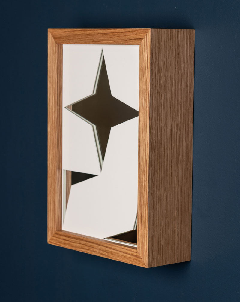 A rectangular mirror with a wooden frame, featuring a powder-coated aluminum lattice design, mounted on a blue wall.
