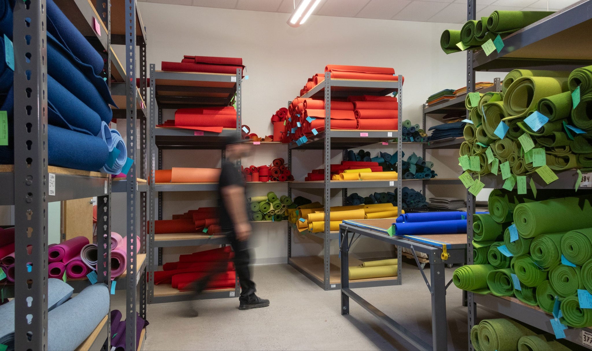 Storage room with shelves filled with colorful wool felt rolls.