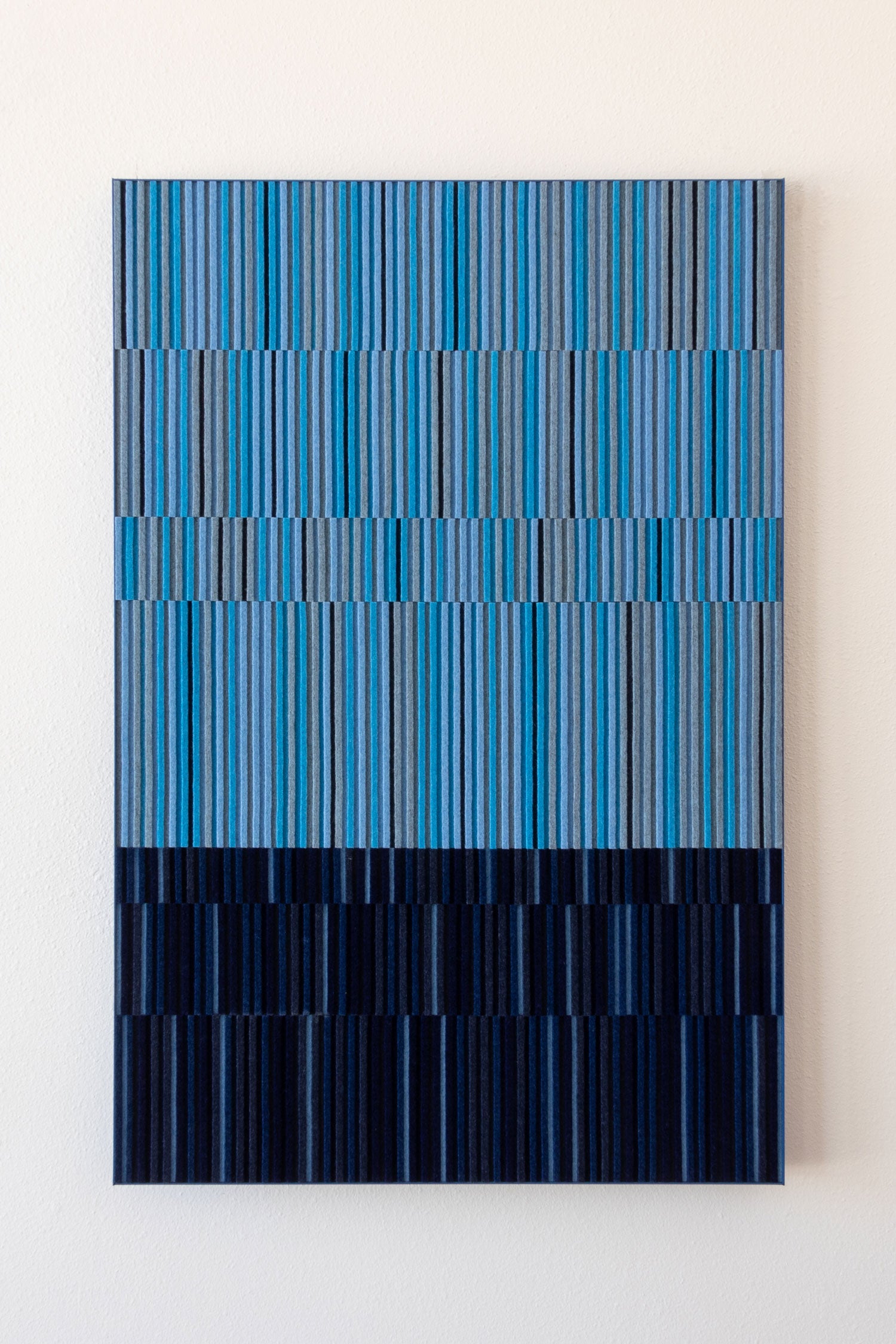 An abstract rectangular wall art piece featuring vertical blue and navy stripes that widen into horizontal bands, displayed against a plain off-white wall. #color_split blues