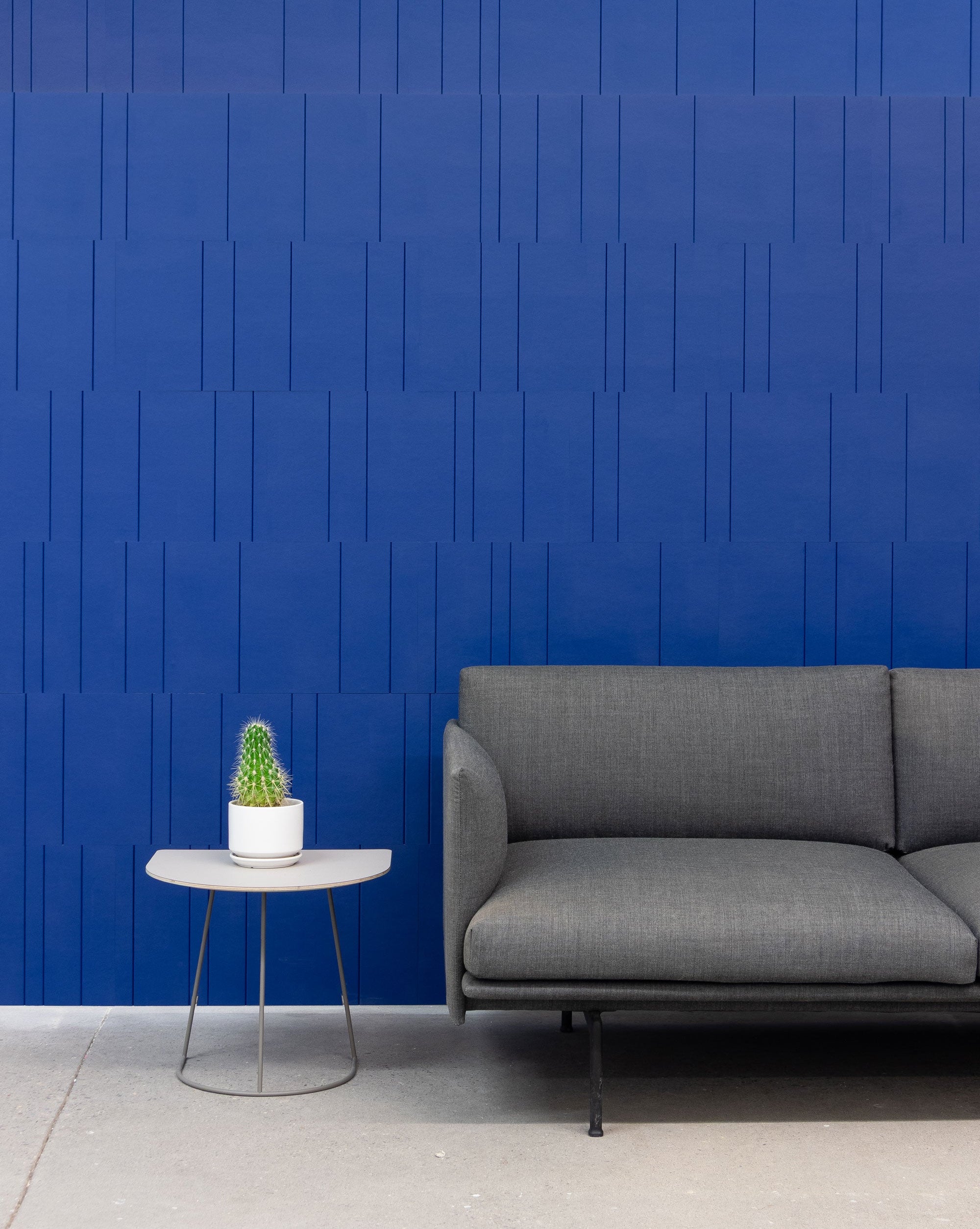 Gray sofa with a small round table and blue cactus leather wall covering.