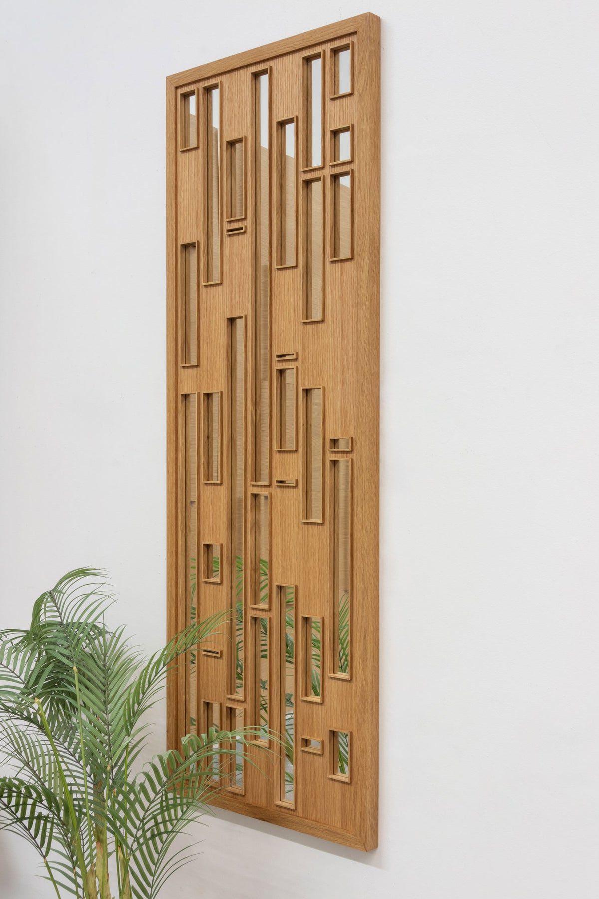 A side view of a wooden mirror in white oak with a veneer face and framed cutout with mirrored glass.