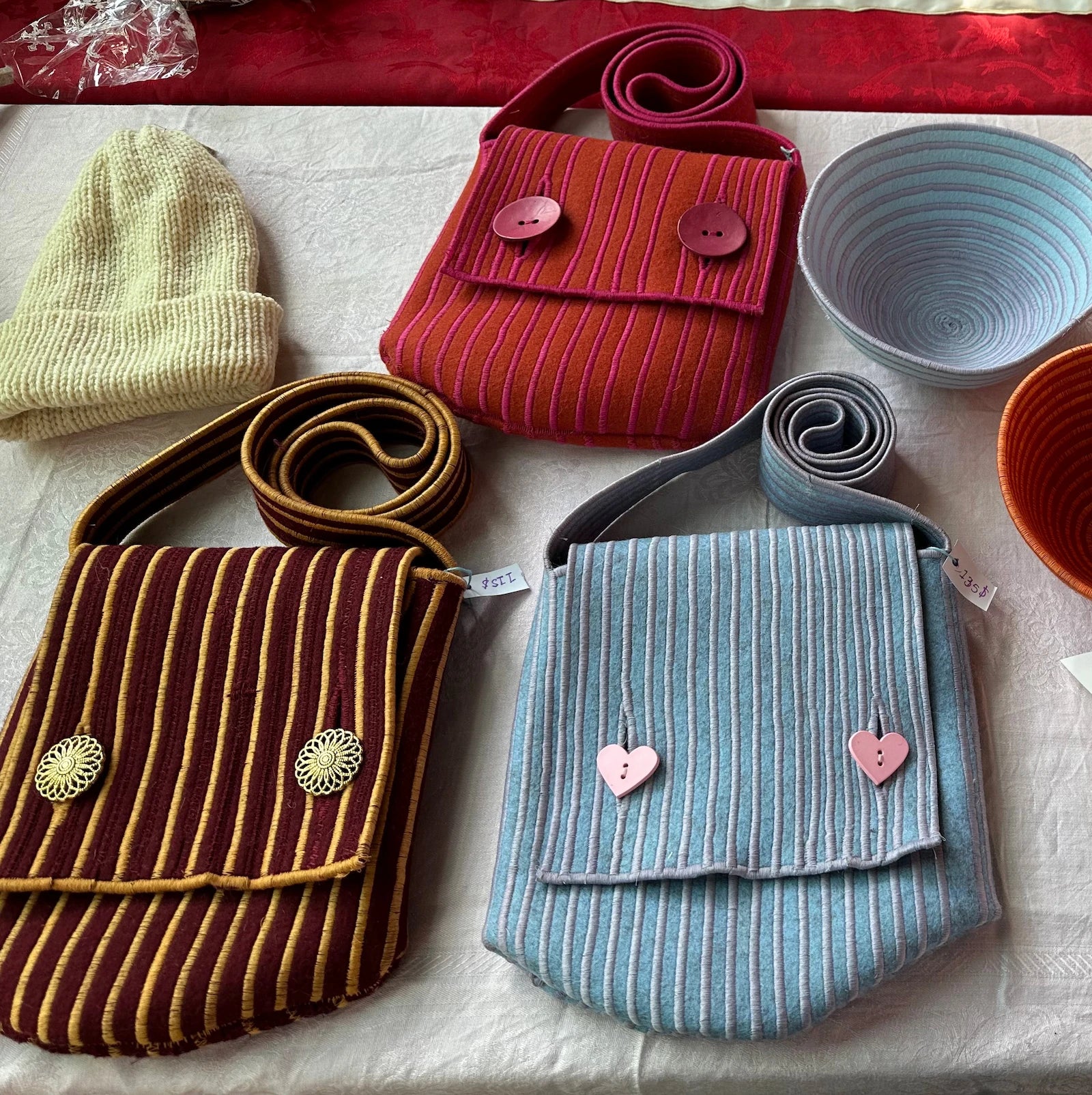 A flat lay of purses and bowls made from thin strips of felt sewn together with thick thread seams.