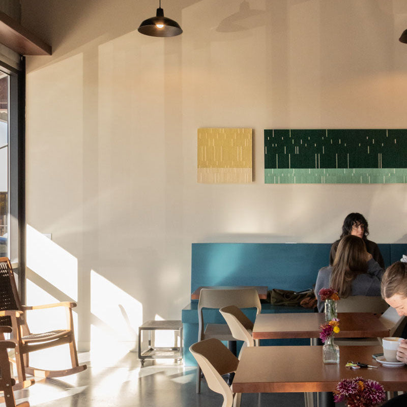 A modern interior space with art hanging on the walls, featuring a prominent rectangular artwork with a pattern of recessed colors.
