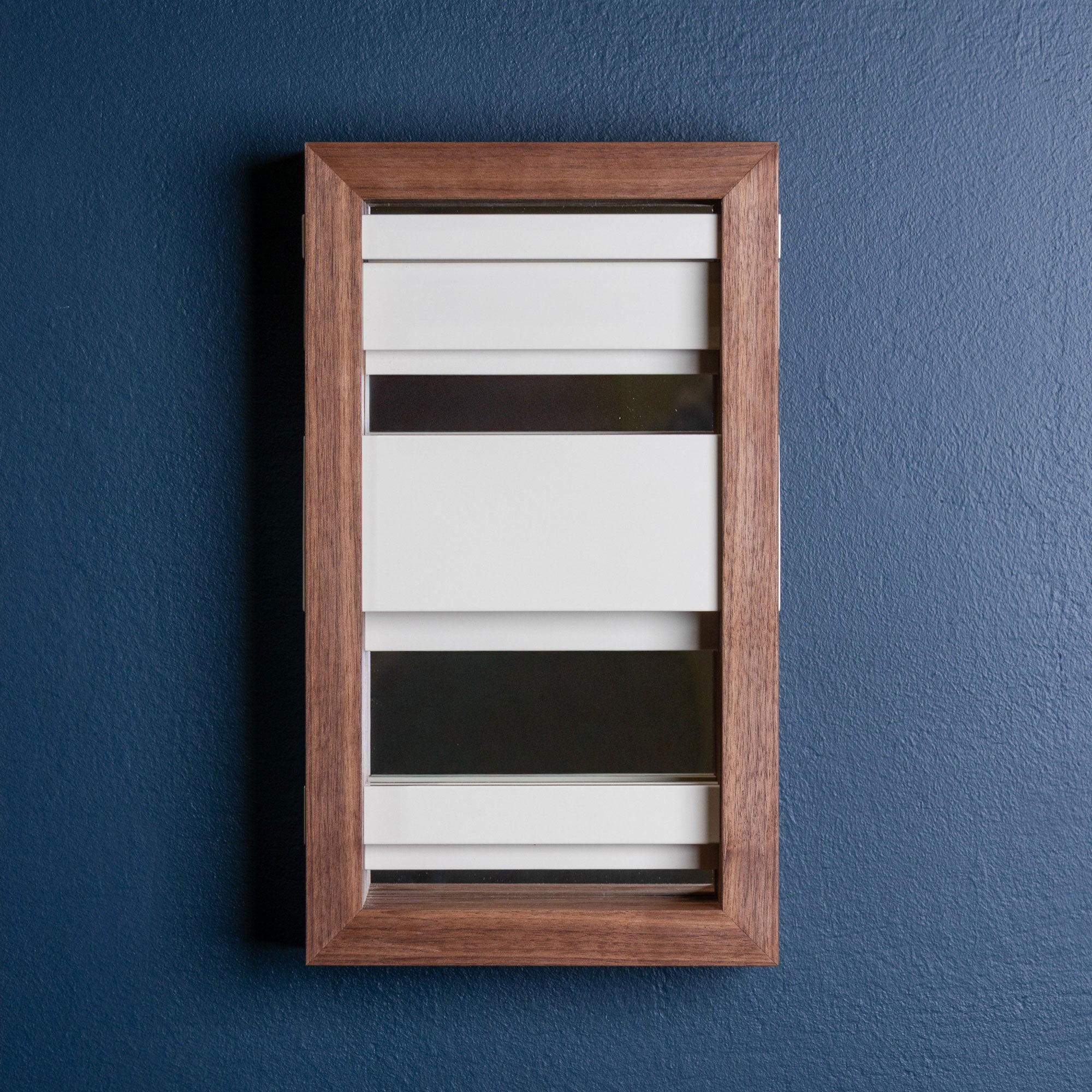 Wooden frame with horizontal white metal slats and mirrored glass on a blue wall