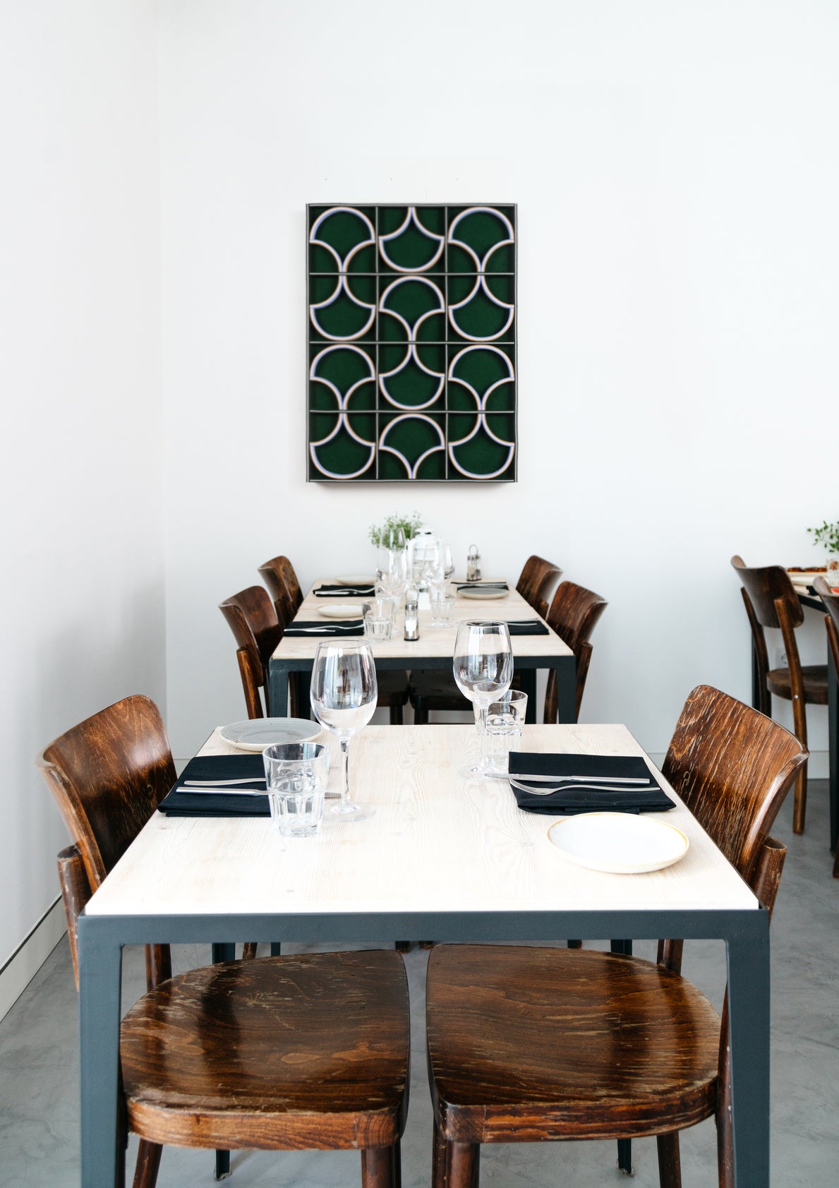 Dining area with tables, chairs, and a decorative green felt wall art piece.