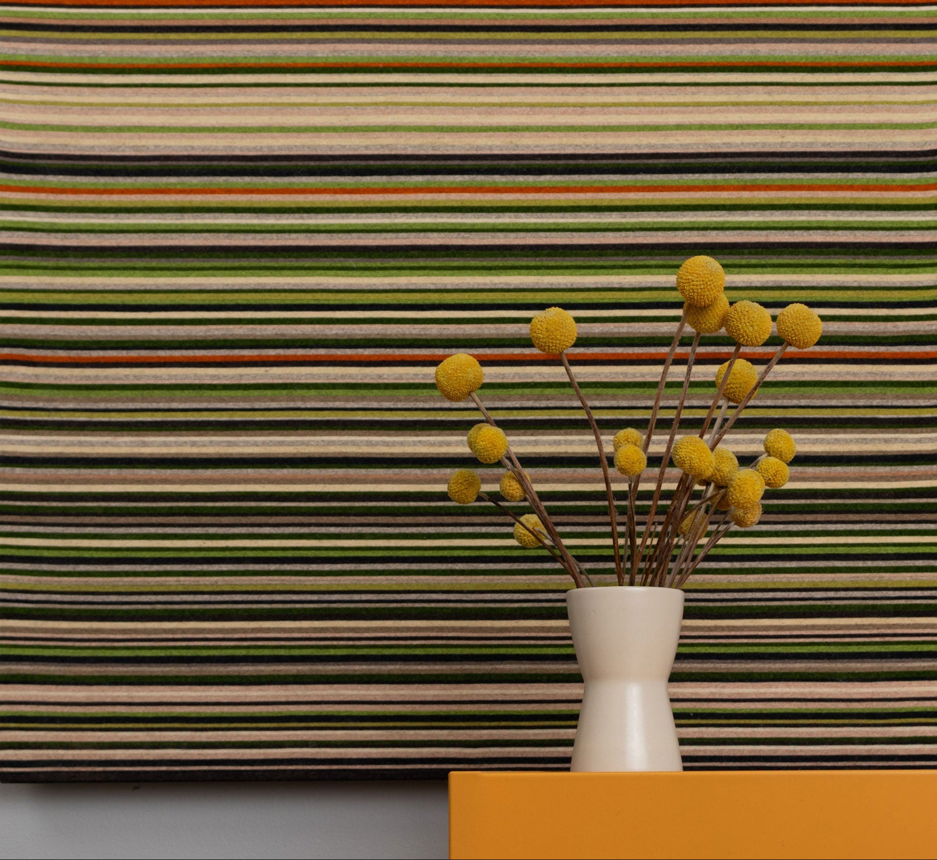 Striped wall art with a vase of yellow flowers on a gray background