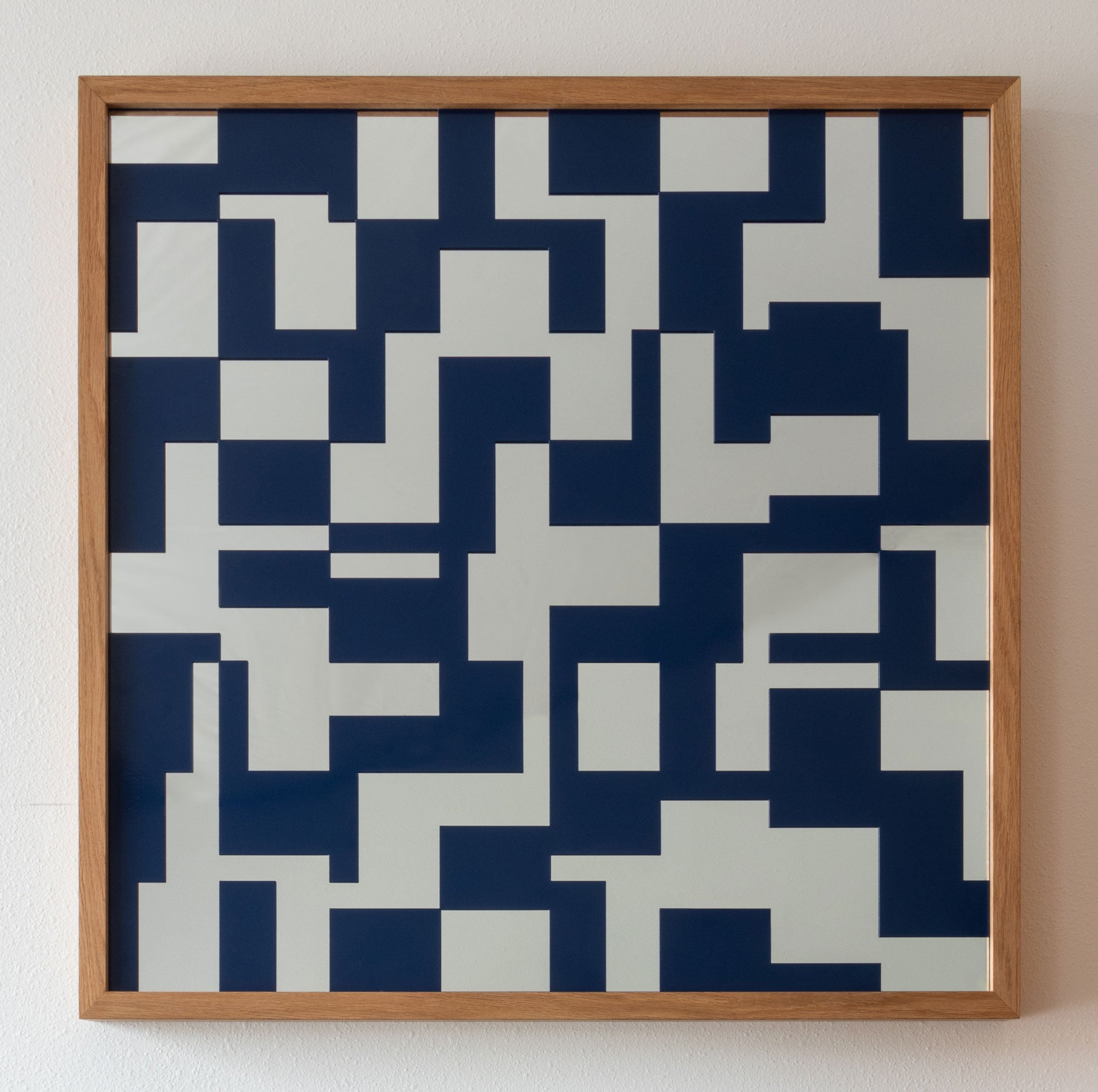 A square modern geometric mirror featuring a navy blue metal lattice with rectangular shapes over a glass mirror, with a light natural wood frame.
#color_sapphire