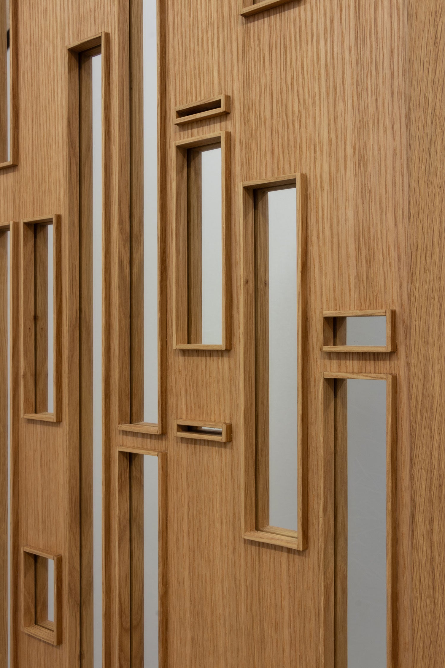 Close up of a wooden mirror in white oak with a veneer face and framed cutout with mirrored glass.