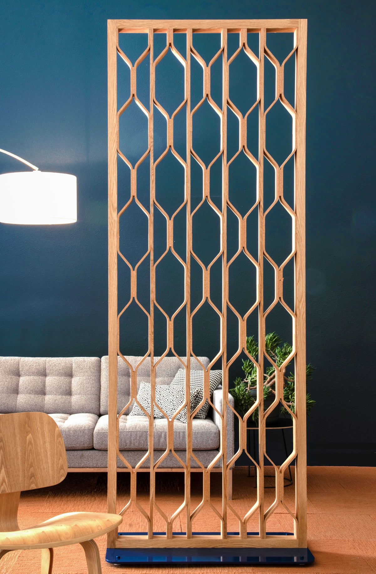 Wooden lattice room divider in a living room setting with a gray sofa and plant.