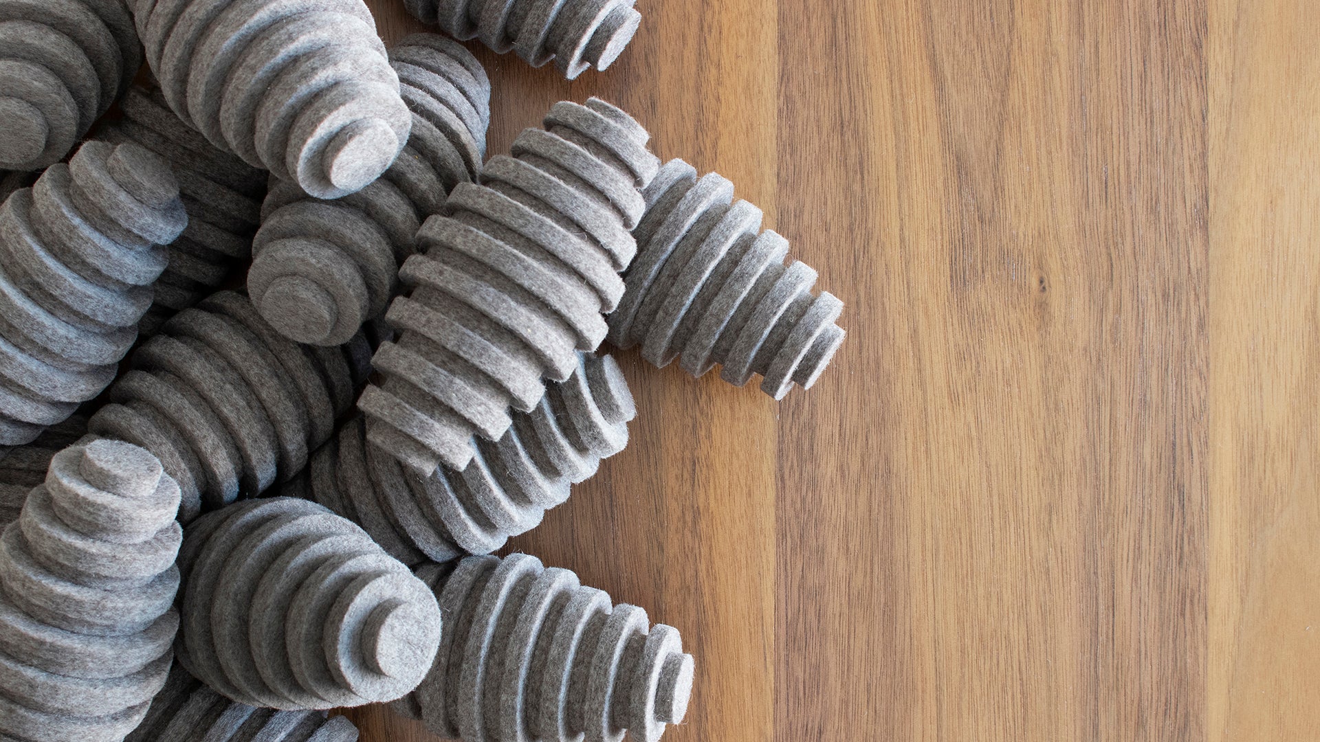 A wooden surface with gray felt pods.