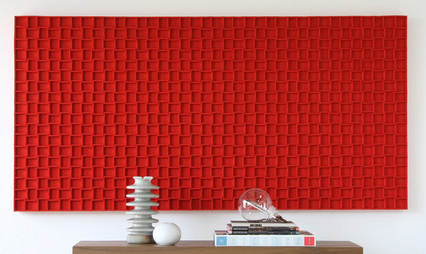 Large rectangular red felt panel with grid pattern hanging behind a table with knick knacks