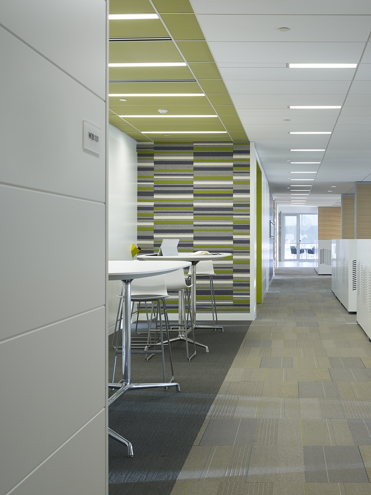 Office space with a blue, gray, and white felt wall covering next to a tall tables