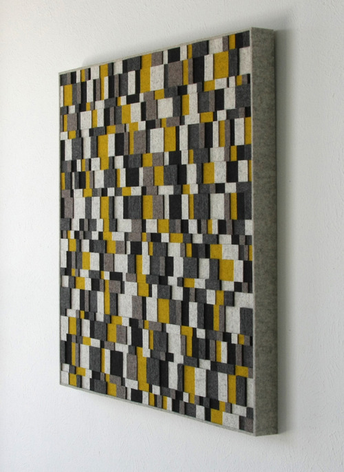 Square felt wall panel seen at an angle with square and rectangle felt pieces in white, gray, yellow, and black.
