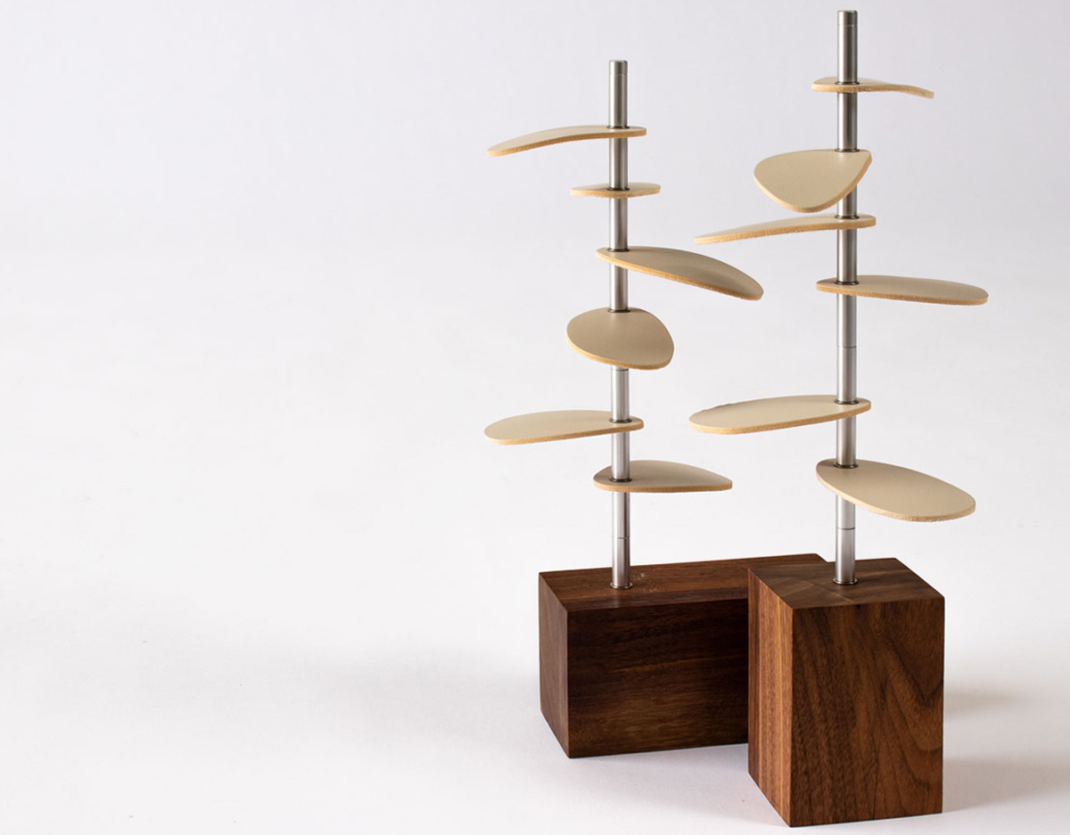 Pair of tree-shaped design pieces with wood bases, metal stems, and white leather leaves.