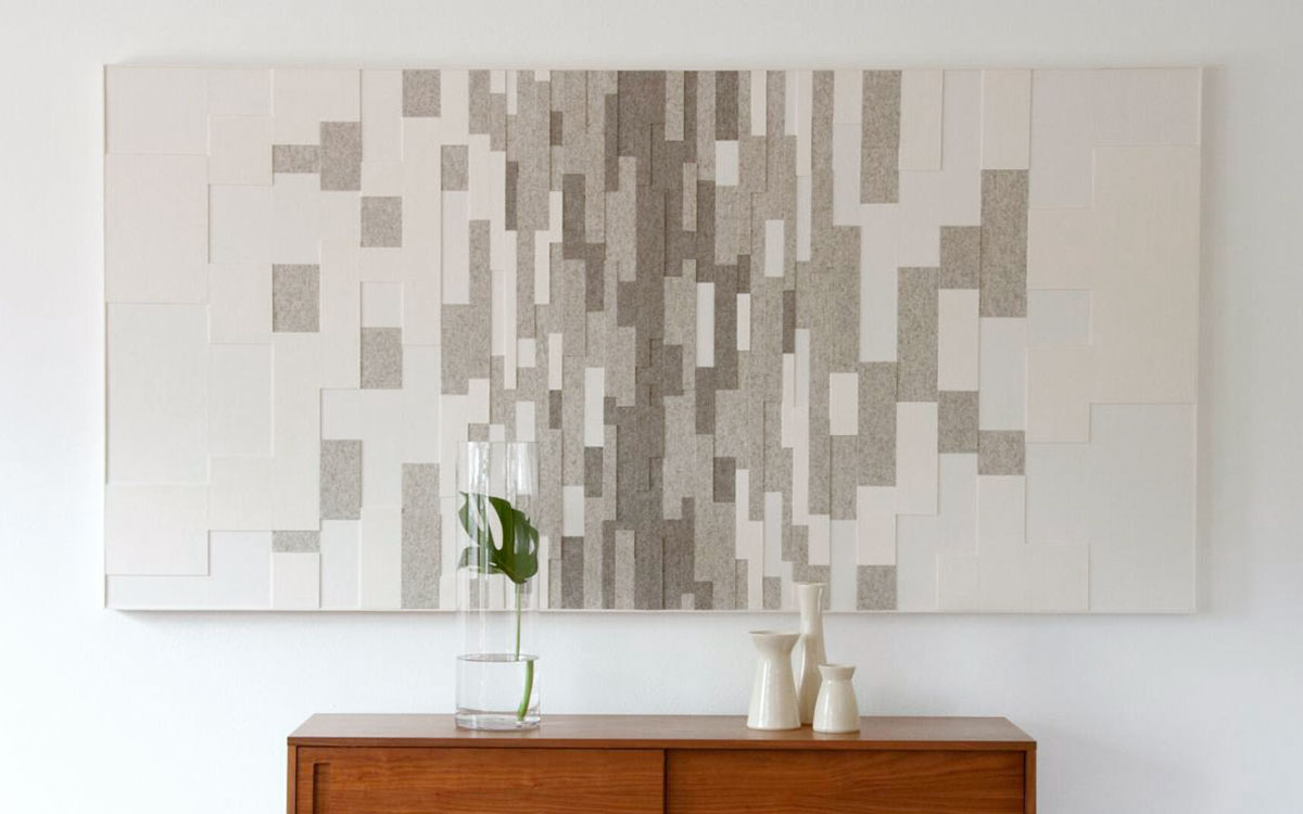 Large rectangular felt wall panel in a gradient pattern from wide white pieces at the edges to narrow dark gray strips at the center