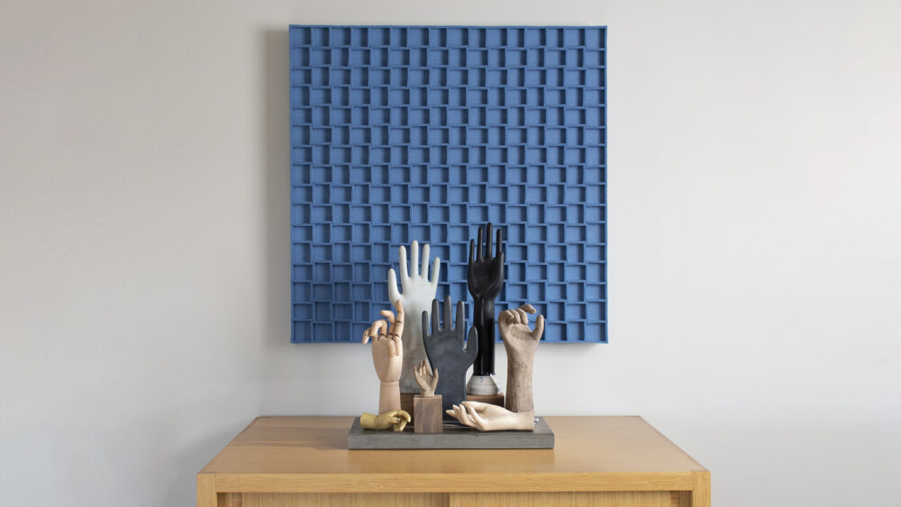 Sky blue square wood felt wall panel with a grid pattern hung above a small table with decorative hand pieces.