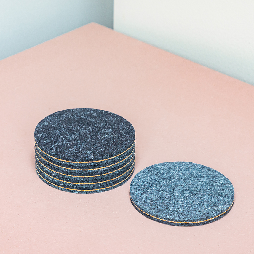 round gray wool felt and cork coasters on a pink table