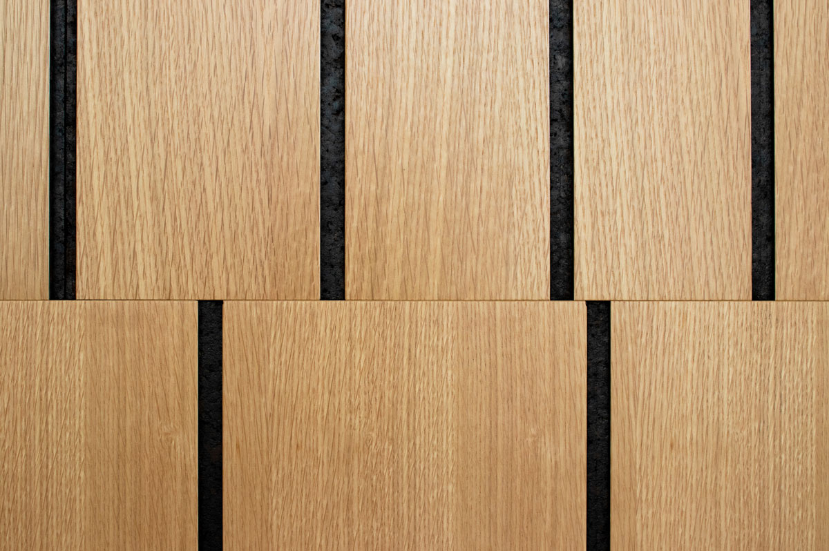 Extreme closeup of two tiles of wall covering in white oak and smoked cork with vertical lines