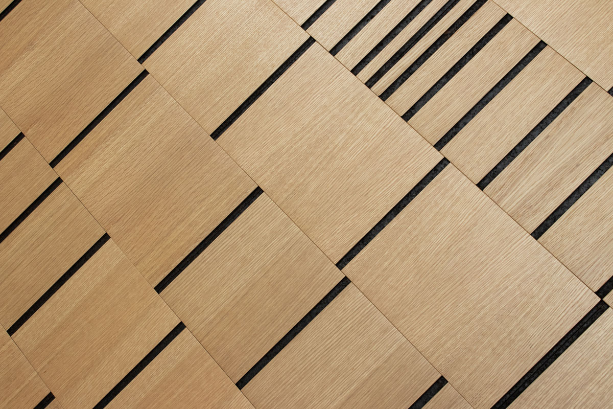 Closeup of wood wall covering in white oak and smoked cork with varying concentrations of vertical lines at random intervals seen at an angle