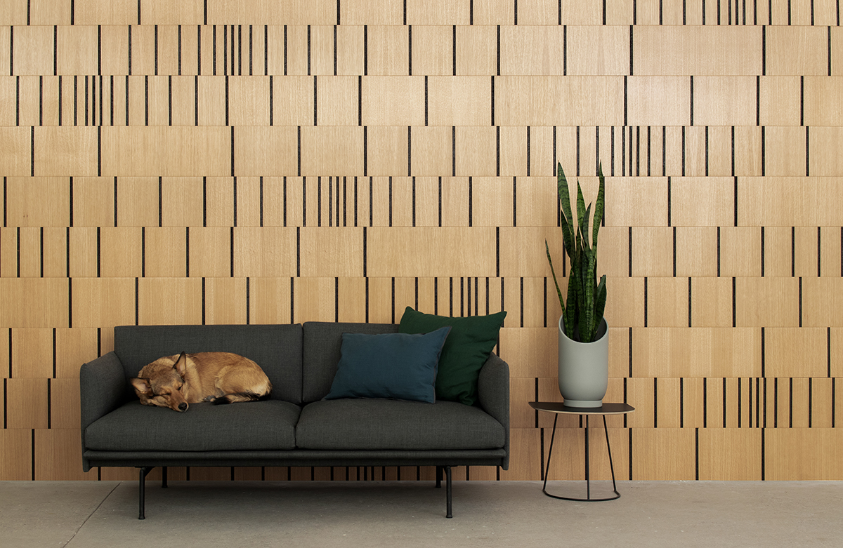 Wood wall covering in white oak and smoked cork with varying concentrations of vertical lines at random intervals. A tan dog sleeps on a gray couch in front of the wall