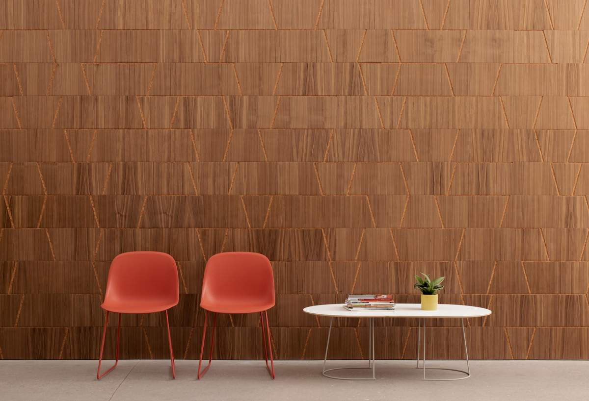 Wood wall covering in walnut and cork with notched out angled lines with two chairs and coffee table