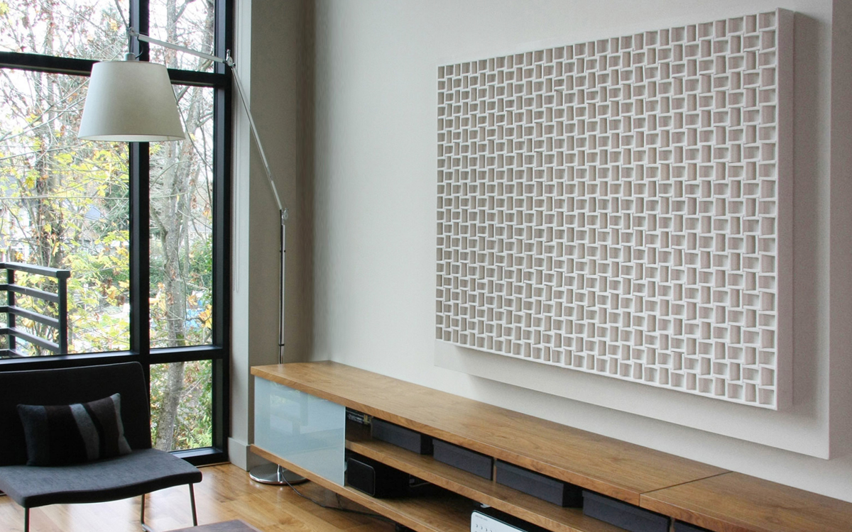 A deeply dimensional white felt grid-like wall panel in an apartment with large windows