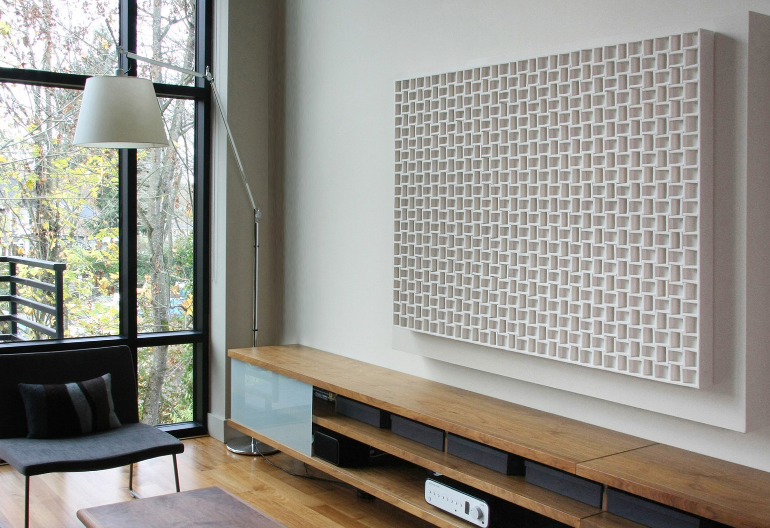 A deeply dimensional white felt grid-like wall panel in an apartment with large windows