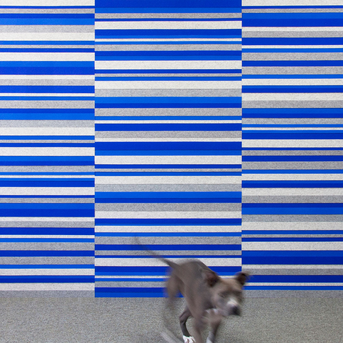Wool felt wall with a pattern of offset horizontal strips in various narrow sizes in blues and grays.