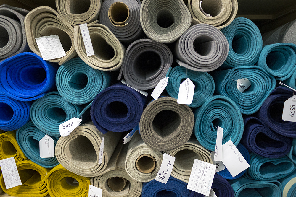 Rolls of felt in blues, grays, and yellows seen at the end of the roll.