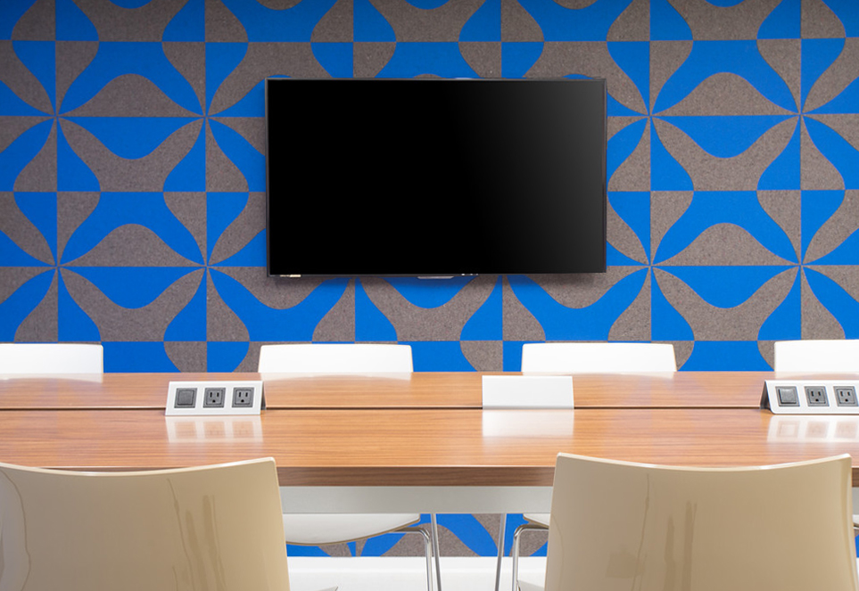 Felt wall covering in blue and gray with thick X pattern. A large screen is seen in the middle of the wall