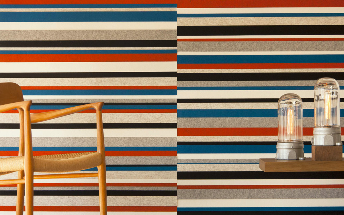 Felt wallcovering with long horizontal stripes in black, blue, red, gray, and white.