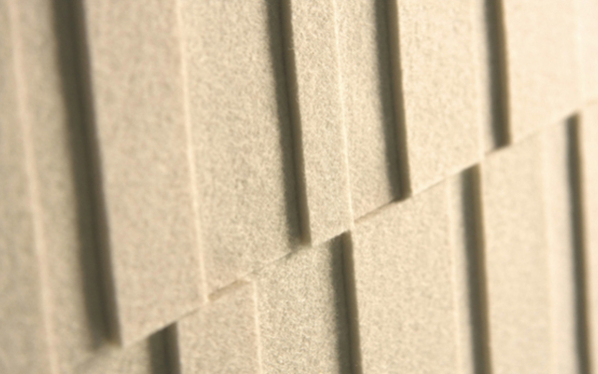 Closeup of cream colored felt wallcovering with different height rectangular pieces.